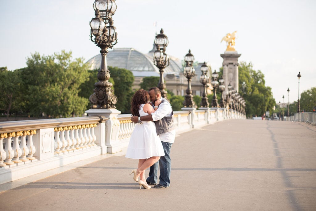 Couple kissing on Pont Alexandre III at sunrise in Paris