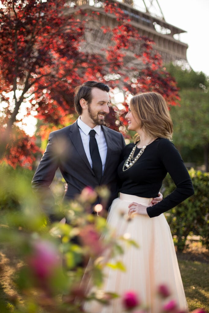 Couple framed by red blossoms with the Eiffel Tower behind them