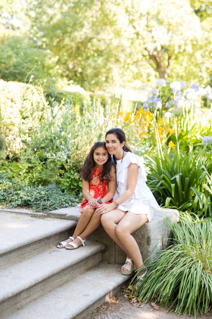 Mother and daughter sitting on stone steps among the flowers at the Real Jardín Botánico in Madrid