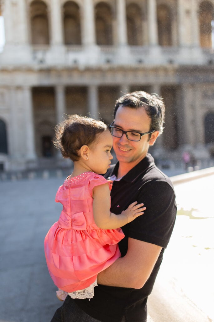 Dad holding his daughter in a pink dress in a Paris courtyard