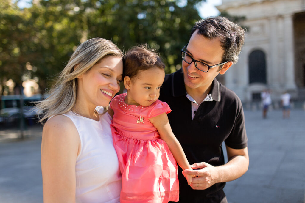 Parents smiling down at their daughter during a family photoshoot in Paris