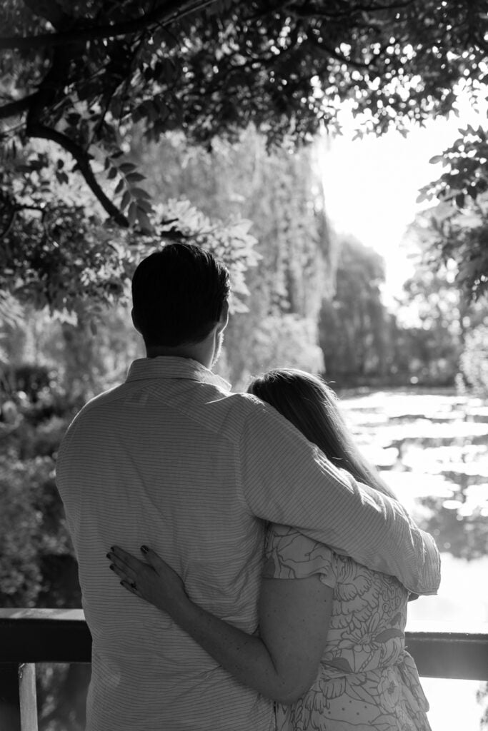 Black and white photo of a couple embracing and looking over the water lily pond in Giverny