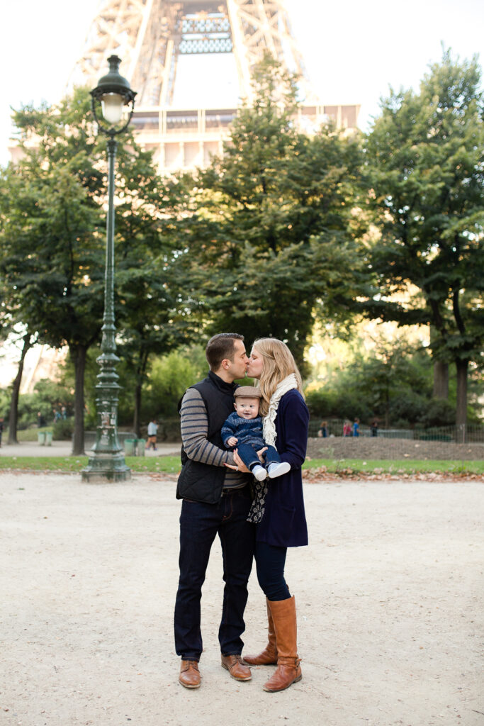 Couple kissing on a path under the trees with the Eiffel Tower above them