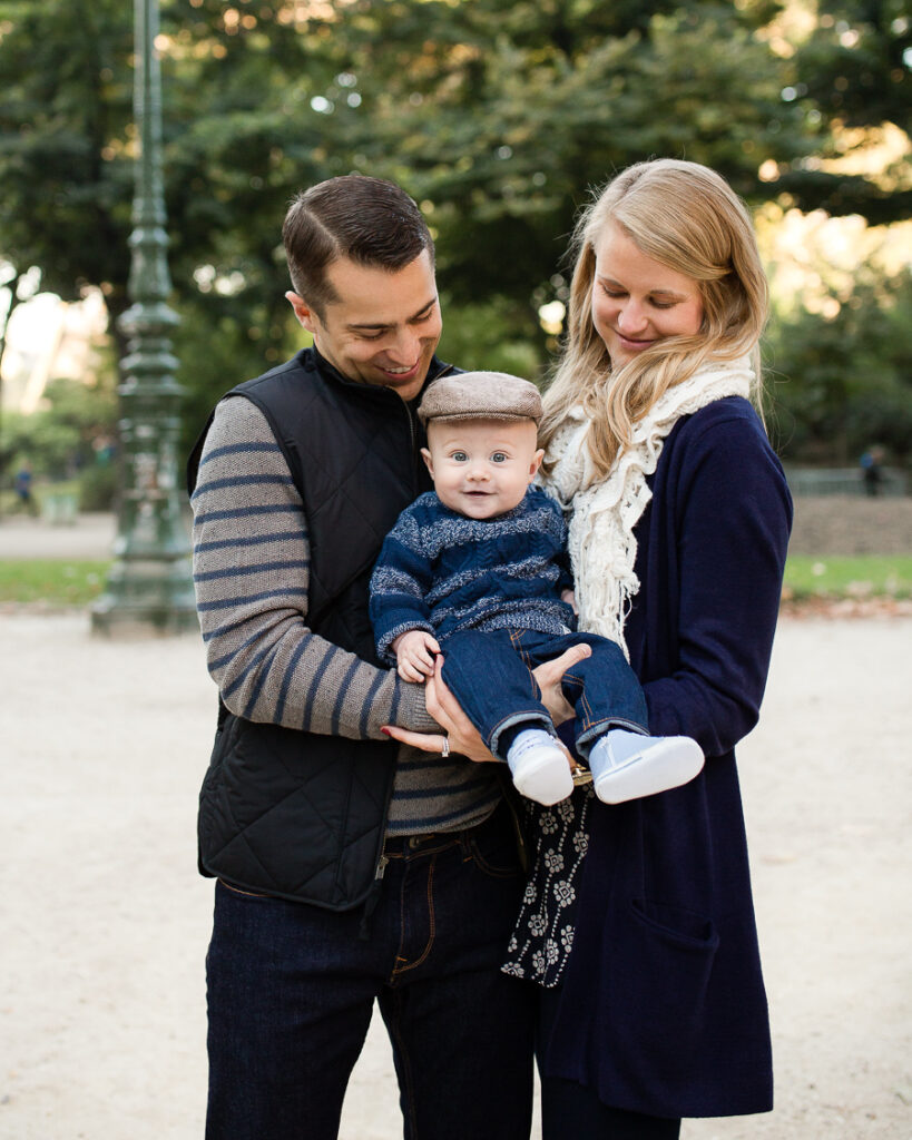 Parents holding their baby by a lamp post in the gardens at the foot of the Eiffel Tower