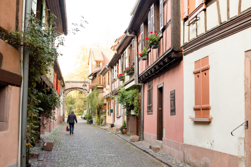 Quiet cobblestone street lined with pink and white houses in Kaysersberg