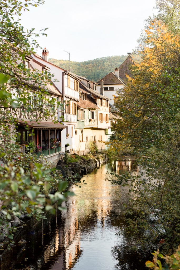 Stream running between old houses and autumn trees in Kaysersberg, Alsace