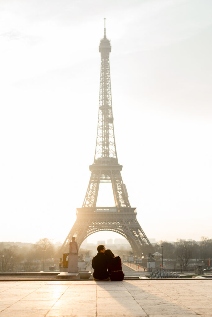 Couple sitting on the wall at Trocadéro looking at the Eiffel Tower at sunrise