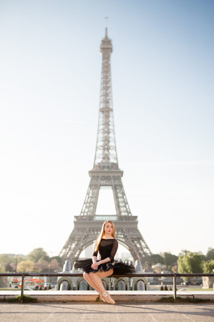 Ballerina in a black tutu sitting on the Trocadéro wall in front of the Eiffel Tower
