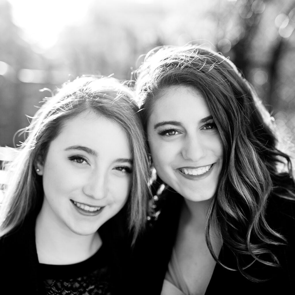 Black and white close-up of two smiling sisters during a Paris family photoshoot