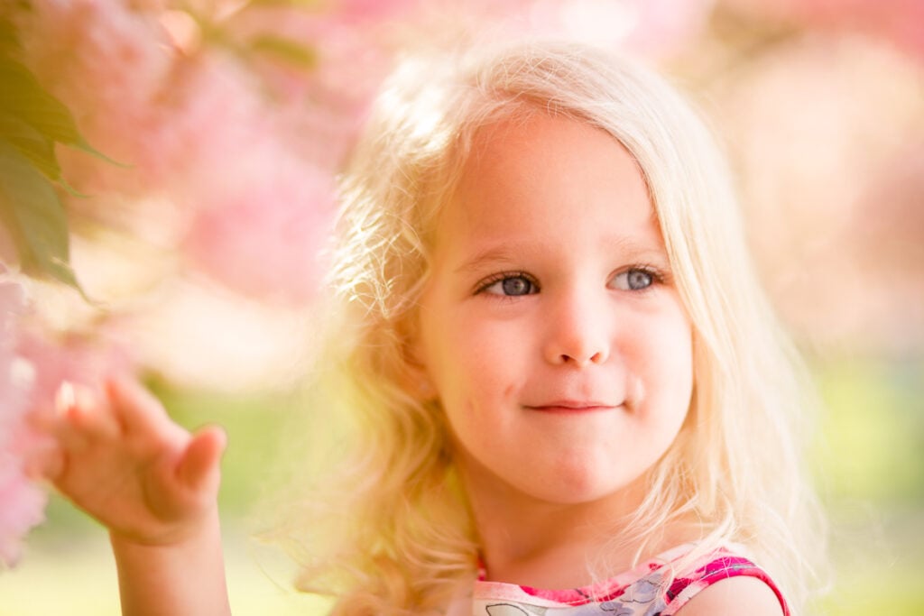 Close-up of a smiling little girl among pink cherry blossoms near Paris