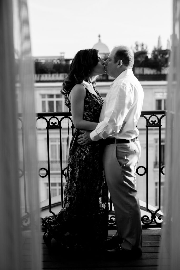 Black and white portrait of couple kissing on balcony at Peninsula Hotel in Paris by Katie Donnelly Photography
