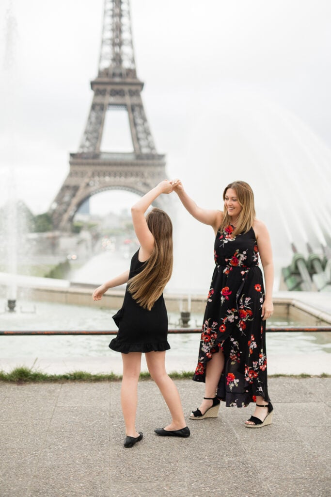 Portrait of mother and daughter twirling at Paris park with fountain: summer packing guide by Katie Donnelly Photography