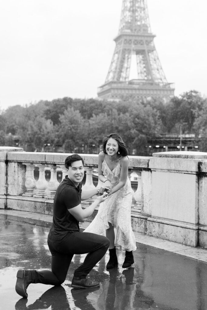 Black and white portrait of young couple proposal on rainy day Paris photoshoot with Eiffel Tower in background by Katie Donnelly Photography