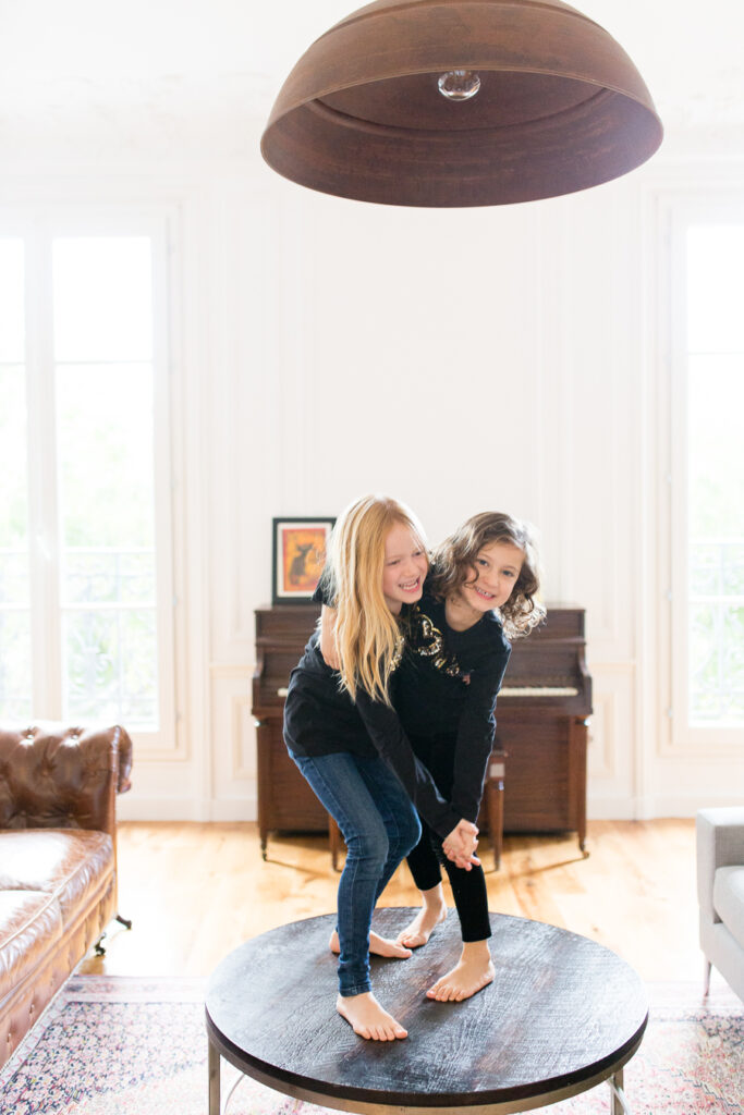 Mother and daughter dancing on a round table in a bright Paris living room