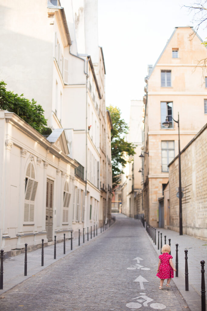 The same little girl looking tiny on a narrow Paris street, photographed from an adult's height