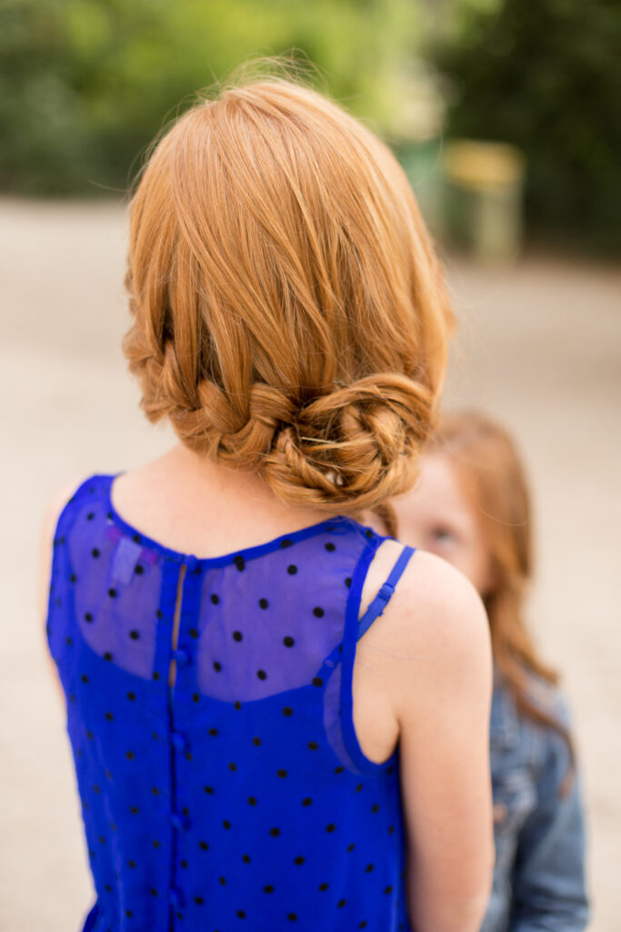 Back view of a girl's braided red hair and bright blue dress