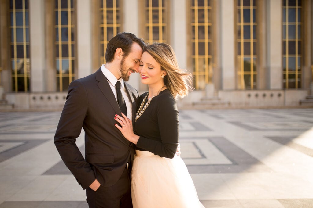 Couple cuddling in front of the columns at Trocadéro during a honeymoon photoshoot