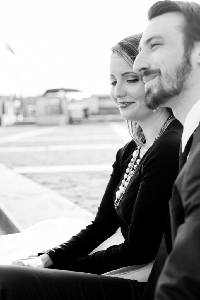 Black and white photo of a couple sitting close together by the Seine