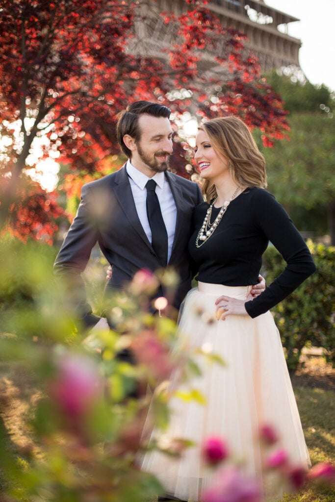 Couple smiling at each other among flowers near the Eiffel Tower in Paris