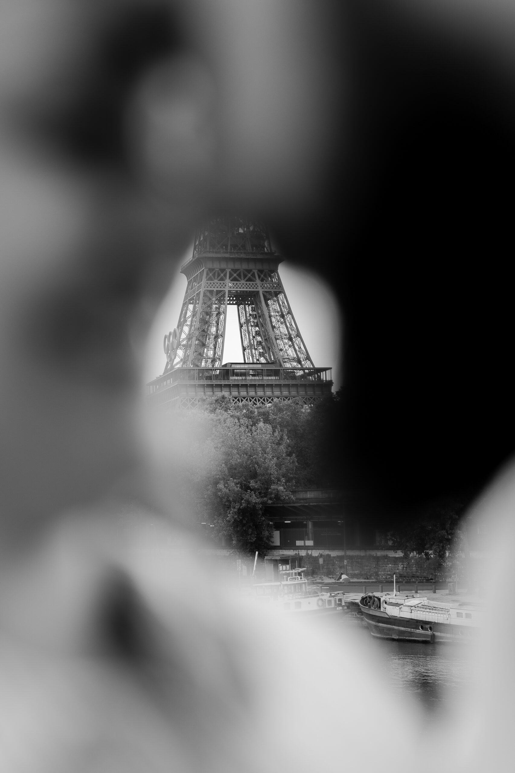 A romantic couple photoshoot on Bir Hakeim Bridge in Paris, captured by Katie Donnelly Photography. The couple is posing under the iconic bridge with the Eiffel Tower in the background.