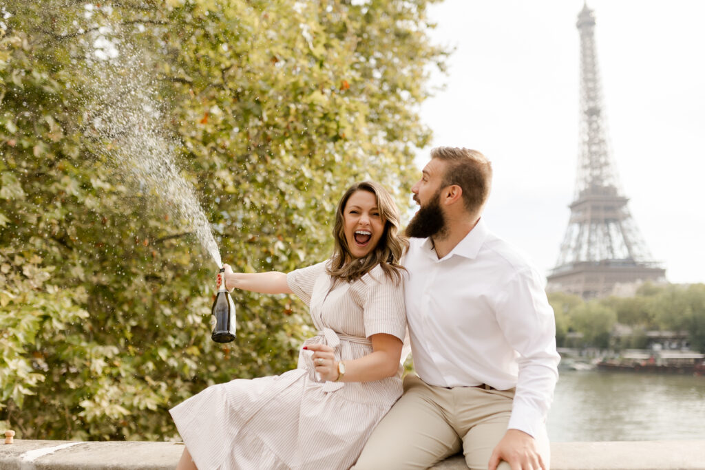 A romantic couple photoshoot on Bir Hakeim Bridge in Paris, captured by Katie Donnelly Photography. The couple is posing under the iconic bridge with the Eiffel Tower in the background.