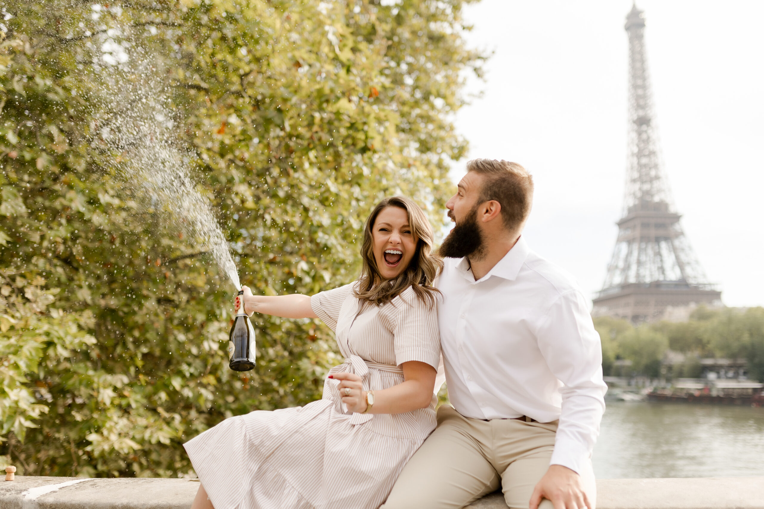 A romantic couple photoshoot on Bir Hakeim Bridge in Paris, captured by Katie Donnelly Photography. The couple is posing under the iconic bridge with the Eiffel Tower in the background.