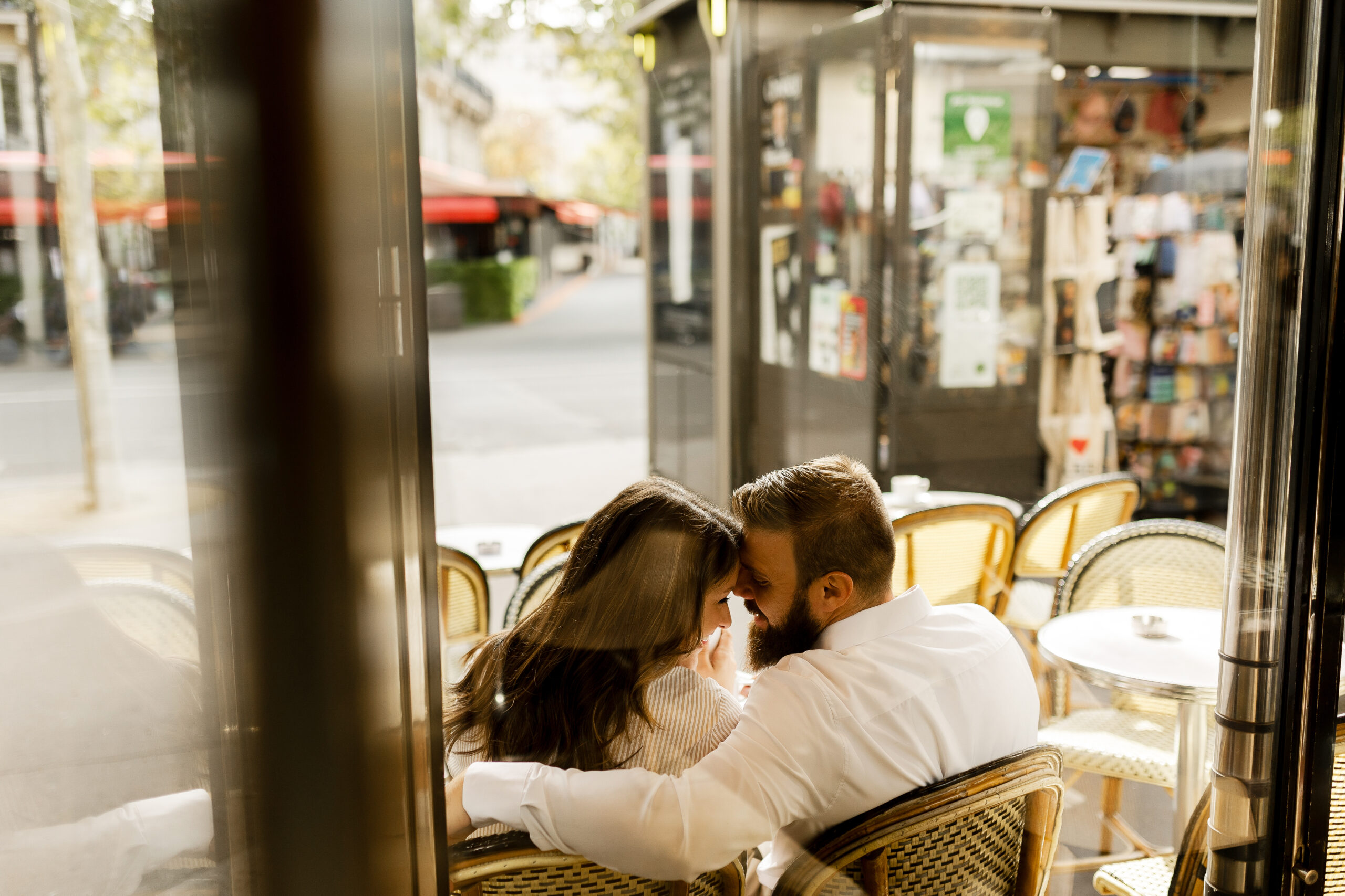 A romantic couple photoshoot on Bir Hakeim Bridge in Paris, captured by Katie Donnelly Photography. The couple is posing under the iconic bridge with the Eiffel Tower in the background.