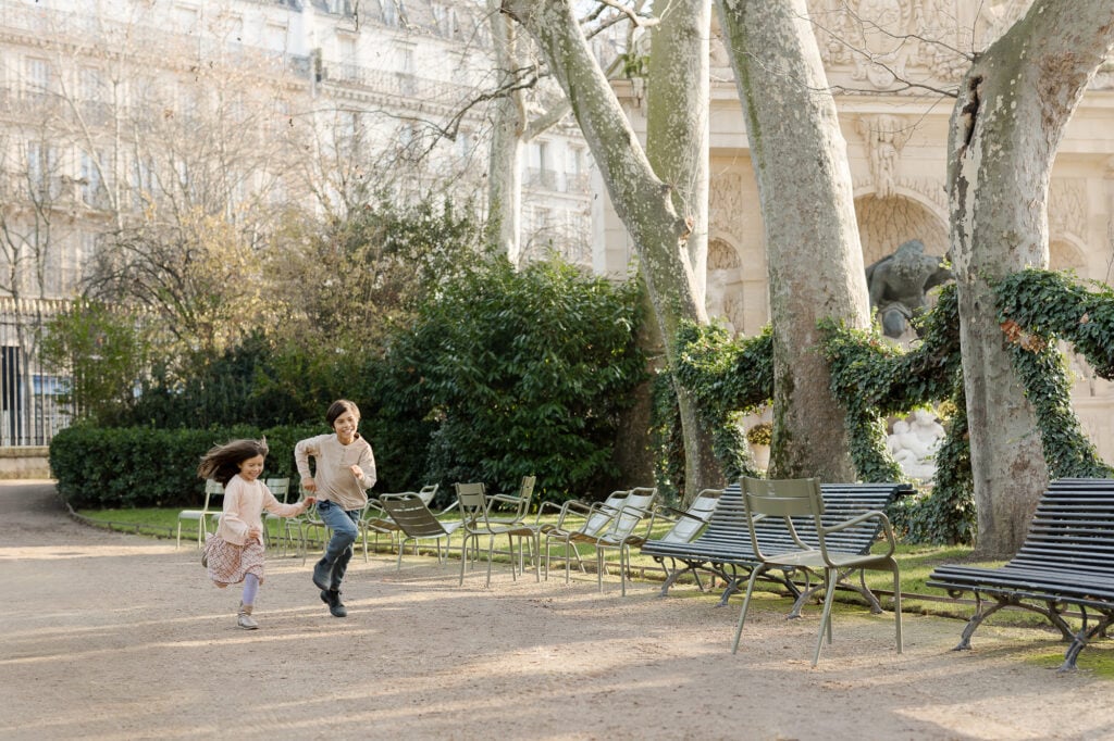 Portrait of two young kids running through Luxembourg garden Paris park by Katie Donnelly Photography