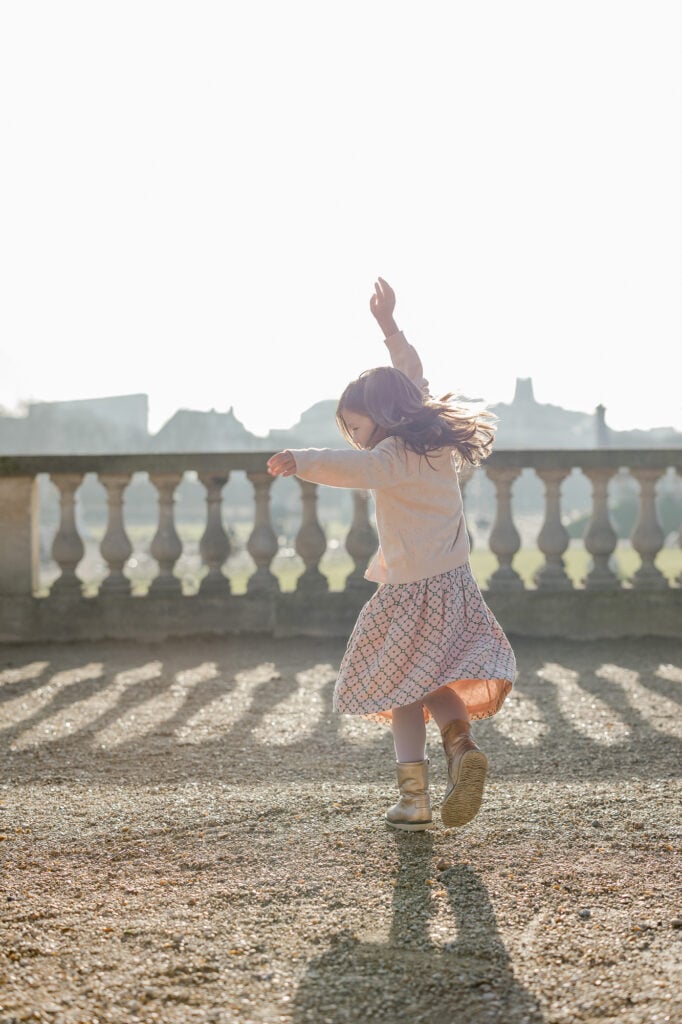 Portrait of young girl running at Luxembourg Garden Paris park by Katie Donnelly Photography