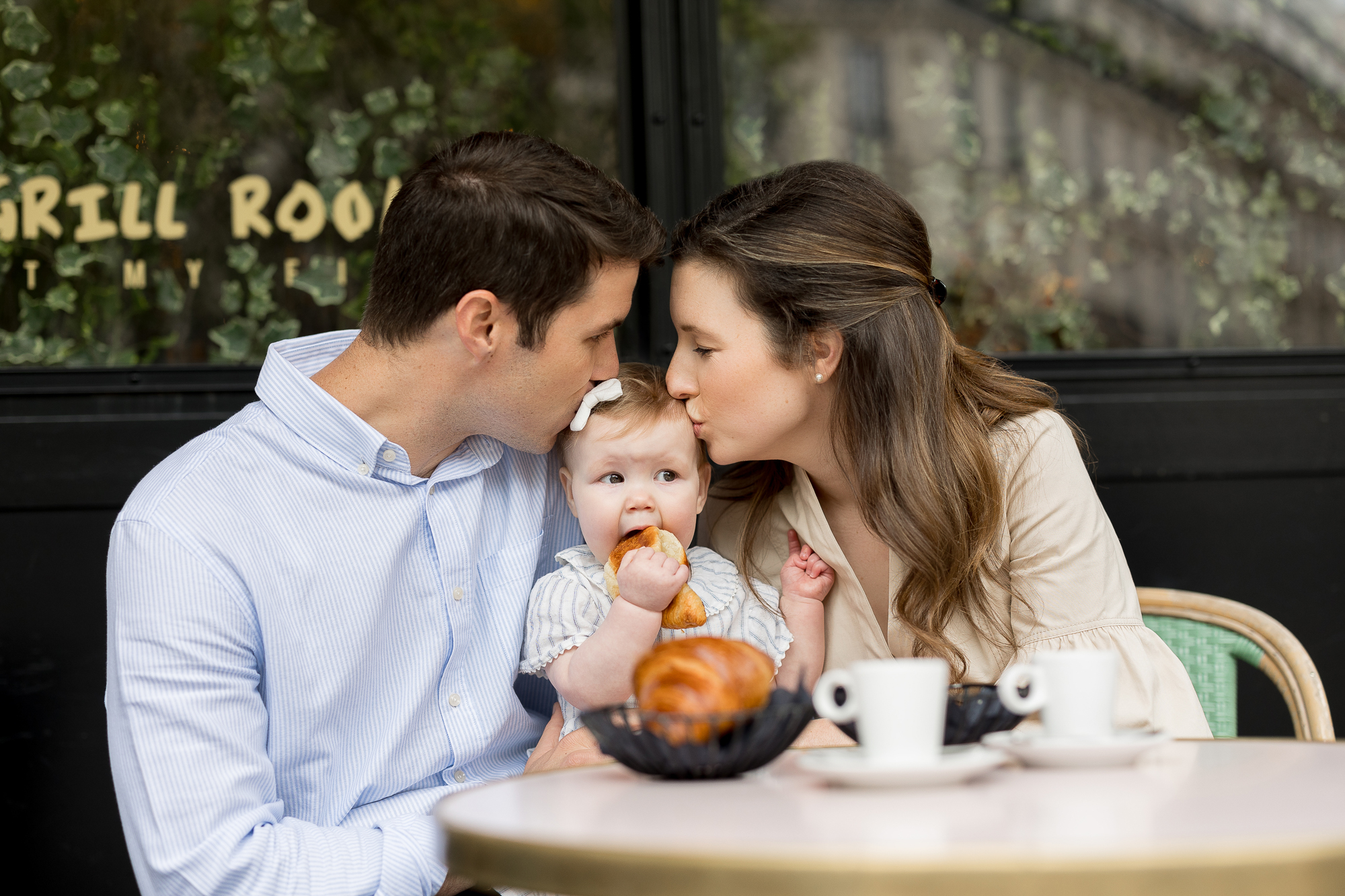 Candid Family photo shoot in Paris with english speaking photographer, Baby eating croissant and parents kissing baby