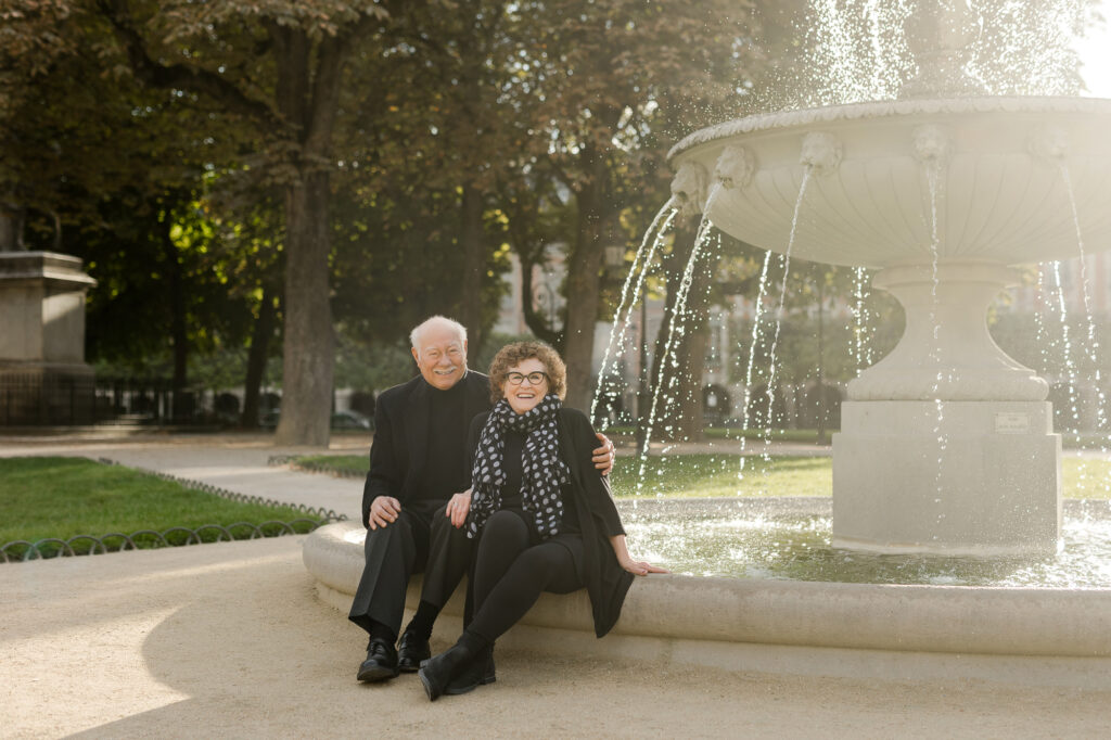 Romantic portrait of elderly couple sitting at fountain at Places des Vosges in Paris by Katie Donnelly Photography