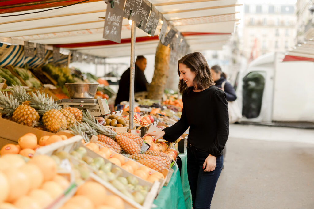 Portrait of woman shopping for oranges at Paris outdoor market by Katie Donnelly Photography