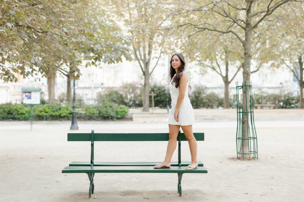 Sweet Sixteen Portrait of teenage girl standing on Paris bench in a white dress by Katie Donnelly Photography
