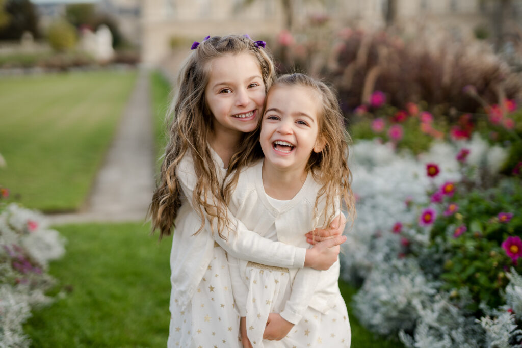 Portrait of young girls hugging at Luxembourg gardens in Paris by Katie Donnelly Photography