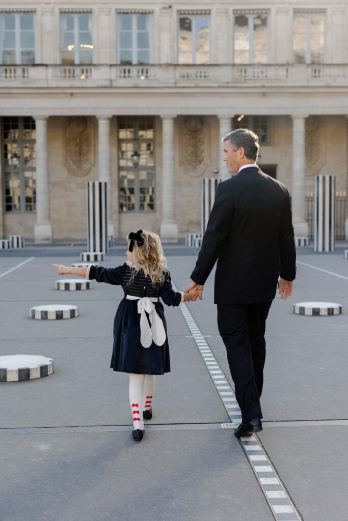 Dad holding daughterโs hand in Paris