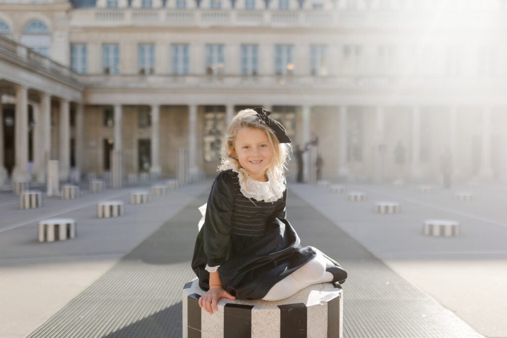 Beginner's Portrait Photography of young girl sitting on column at Palais Royal in Paris by Katie Donnelly Photography