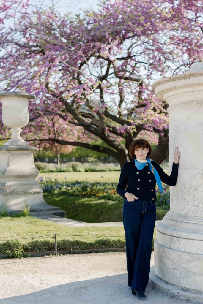 Portrait of woman leaning against pillar with cherry blossoms in background in Paris by Katie Donnelly Photography