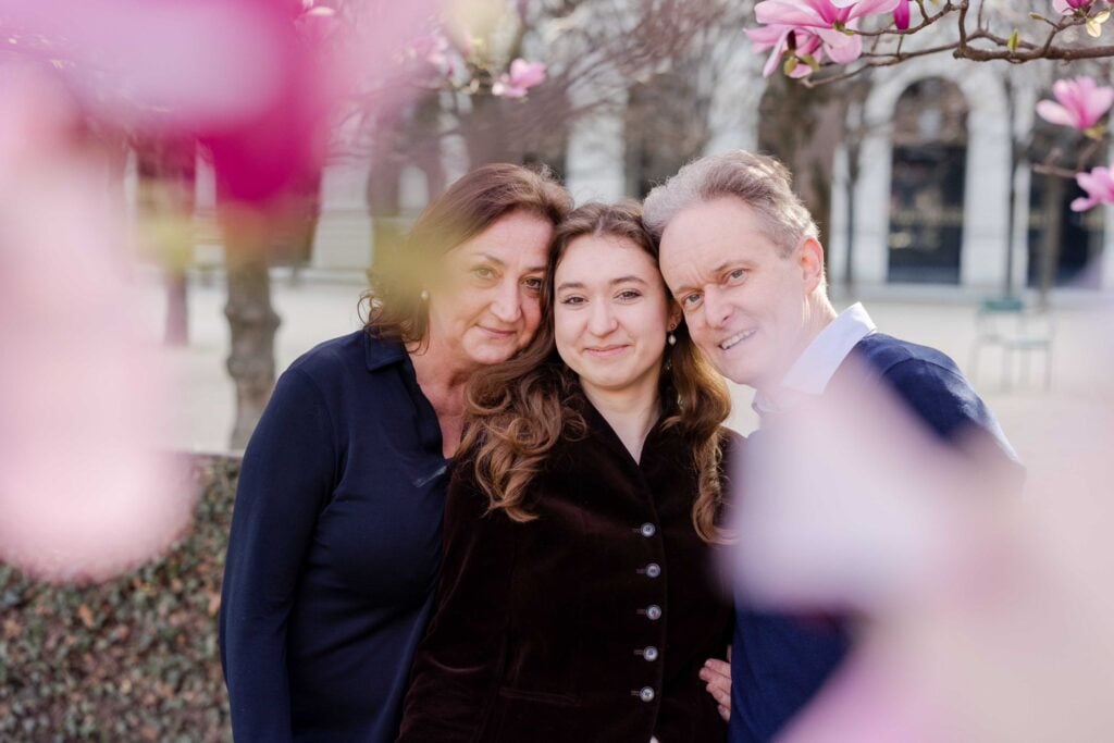 Portrait of family smiling together in park during spring magnolia flower blossoms in Paris by Katie Donnelly Photography