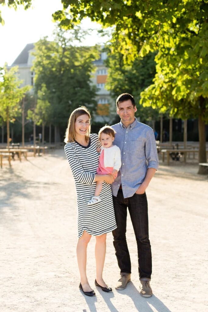 Family of three standing together in coordinated outfits in the Luxembourg Gardens, Paris