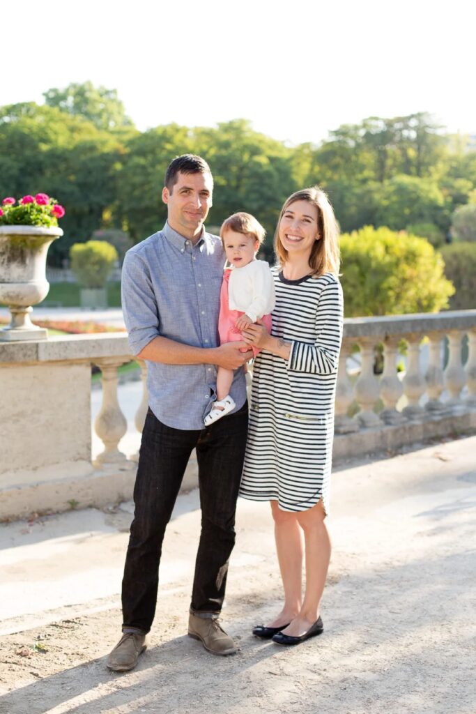 Family portrait by a stone balustrade in the Luxembourg Gardens with outfits in blue, grey and pink