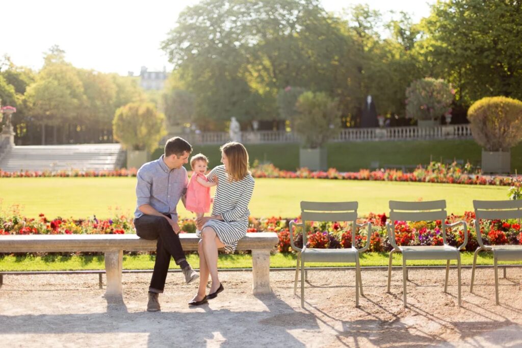 Parents and baby sitting on a bench in the Luxembourg Gardens in coordinated outfits