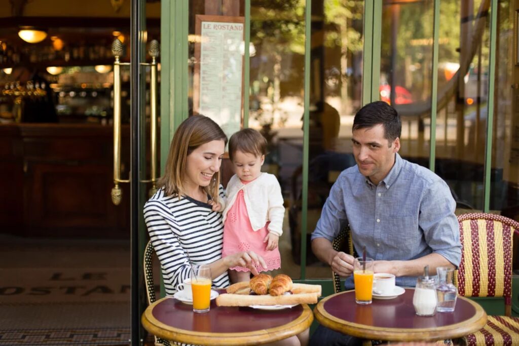 Family having breakfast at a Paris café terrace during their family photoshoot