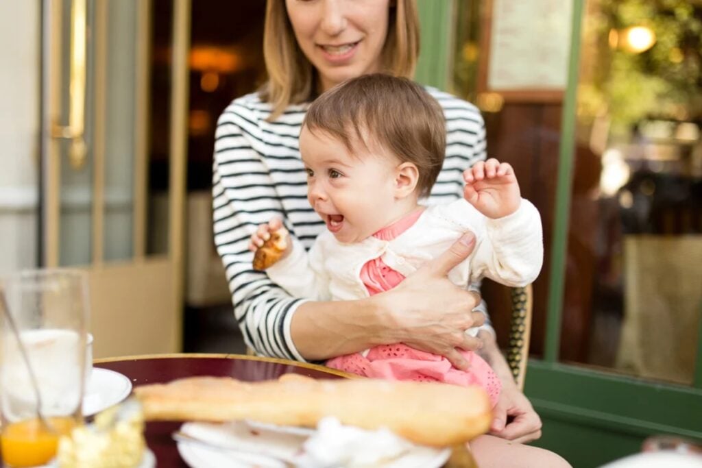 Mother holding her laughing baby at a Paris café