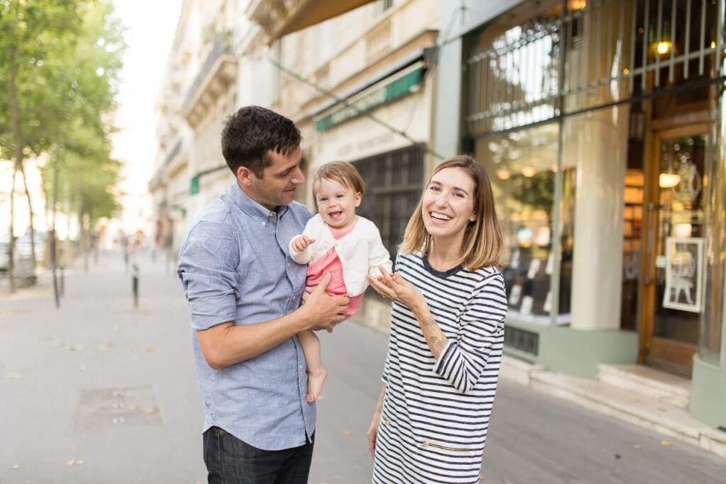 Family walking down a Paris street, baby in Dad's arms, in coordinated striped and chambray outfits