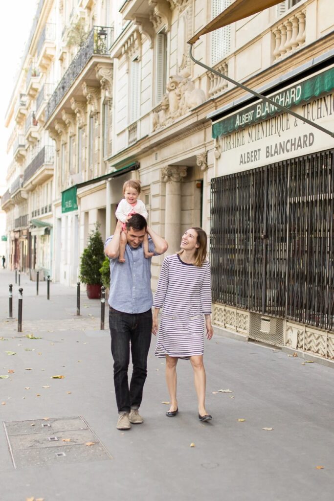 Dad carrying his baby on his shoulders as the family walks down a Paris street