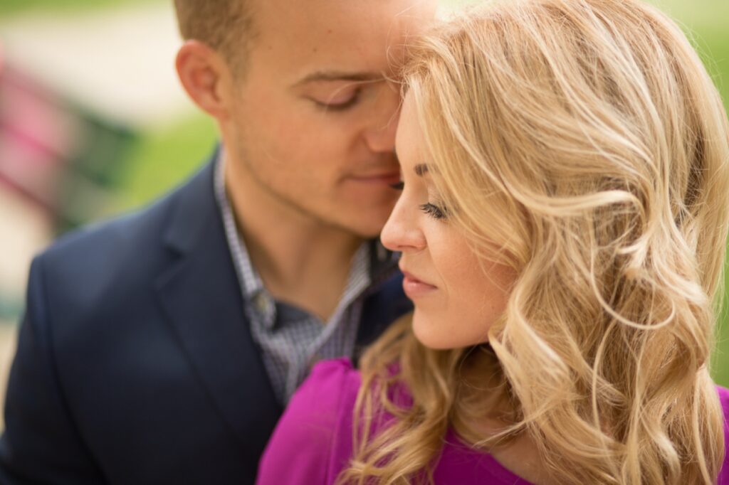 Close-up of an expecting couple with eyes closed, heads together, in a Paris garden