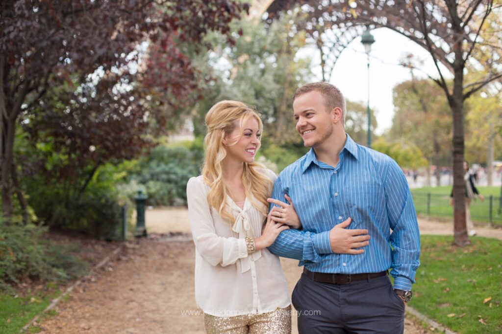 Couple smiling under the trees in the gardens at the foot of the Eiffel Tower