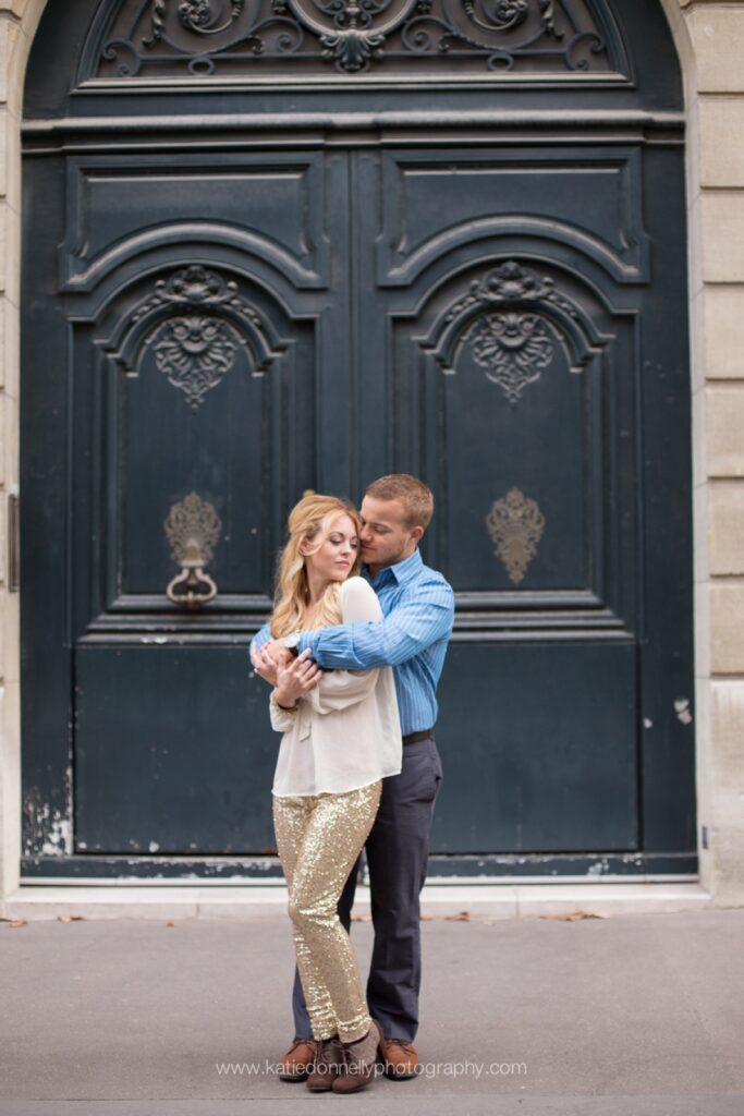 Couple hugging in front of a tall navy blue Parisian door