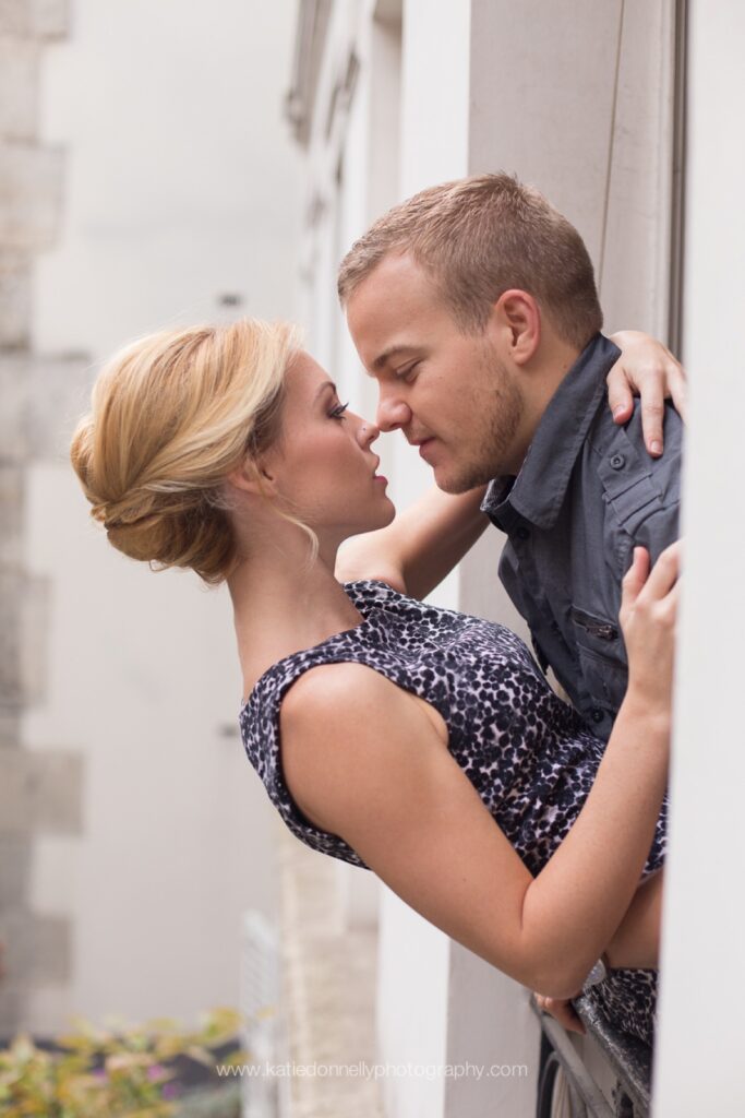 Couple about to kiss, leaning against a white Parisian doorway