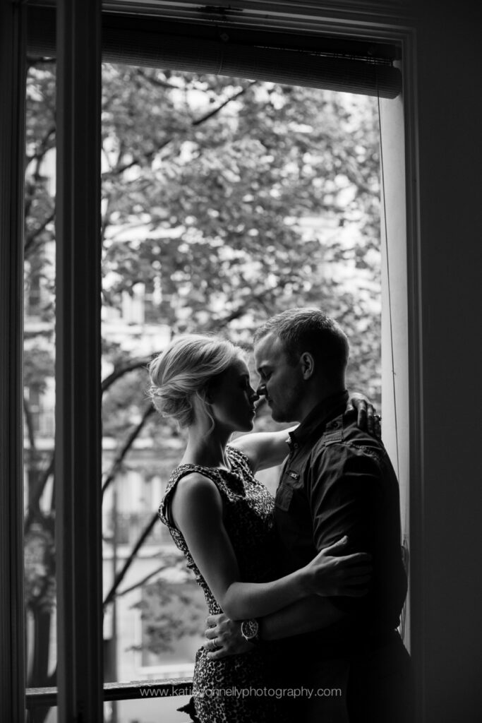 Black and white silhouette of a couple embracing in a doorway overlooking a garden